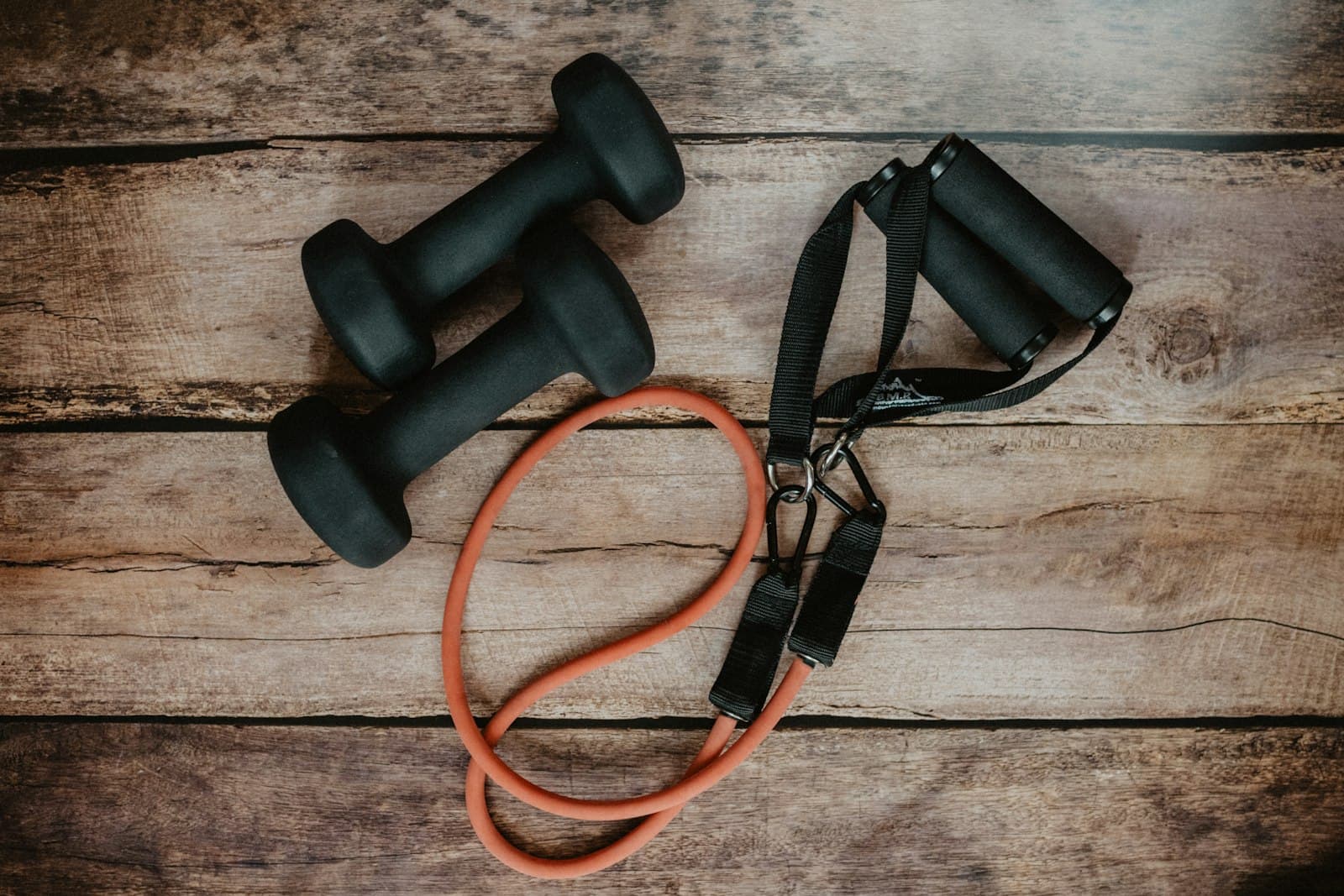 A pair of dumbbells and a resistance band on a wooden floor