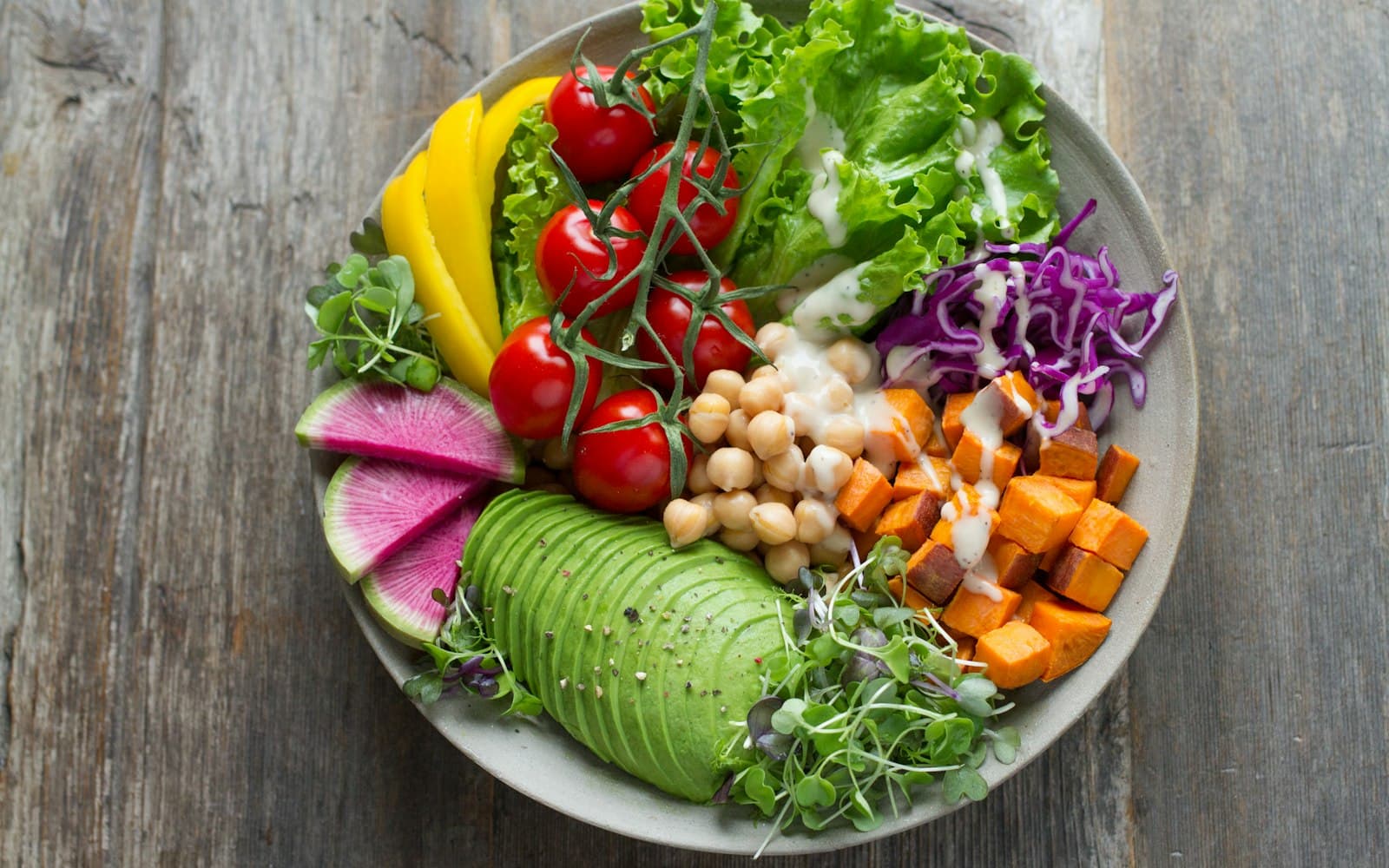 A bowl of salad with avocado, chickpeas, tomatoes, peppers and red cabbage